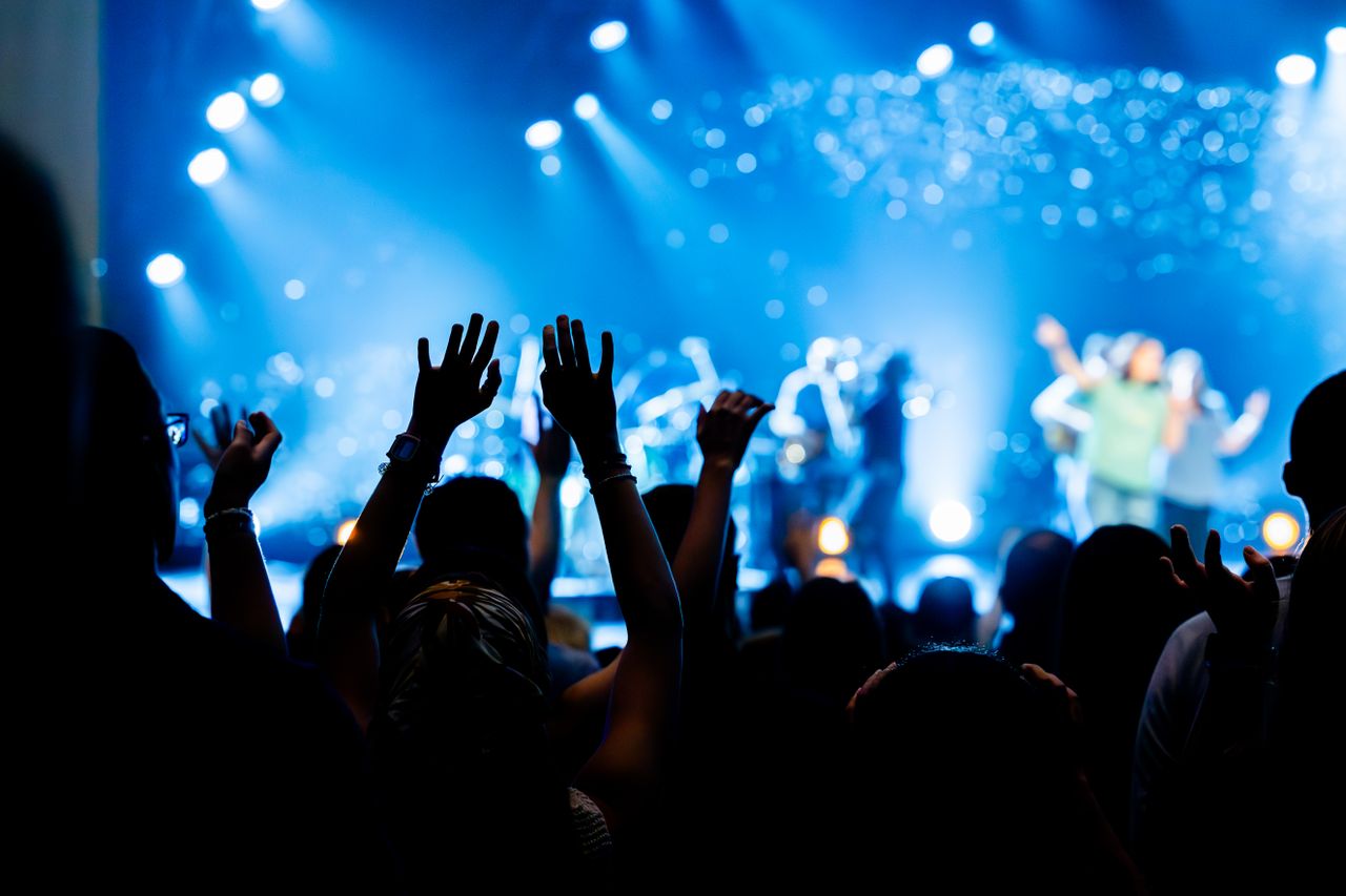 Vibrant concert scene with audience raising hands, enjoying live music.