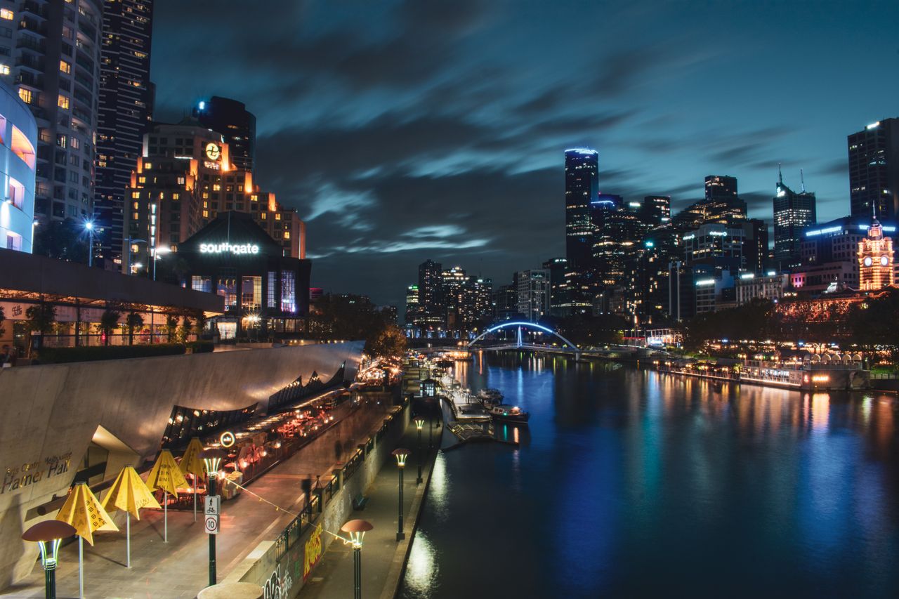 Melbourne's skyline illuminated at night, reflecting vibrant city lights on the Yarra River.