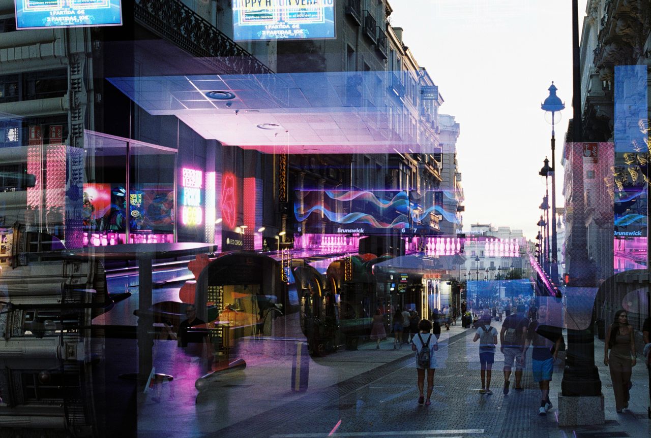 Colorful urban street with neon reflections and people walking at twilight.