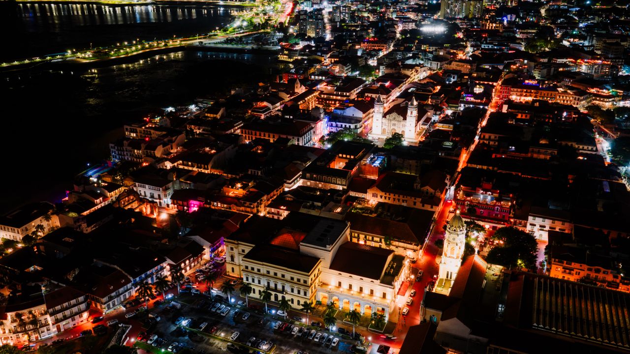A vibrant aerial view of Panama City glowing with lights at night, showcasing its dynamic urban landscape.