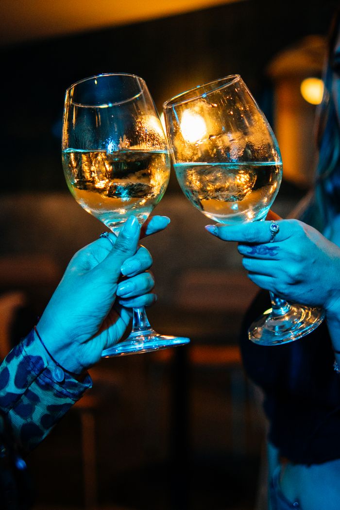 Two people toasting with wine glasses in a Buenos Aires bar, celebrating in a vibrant setting.