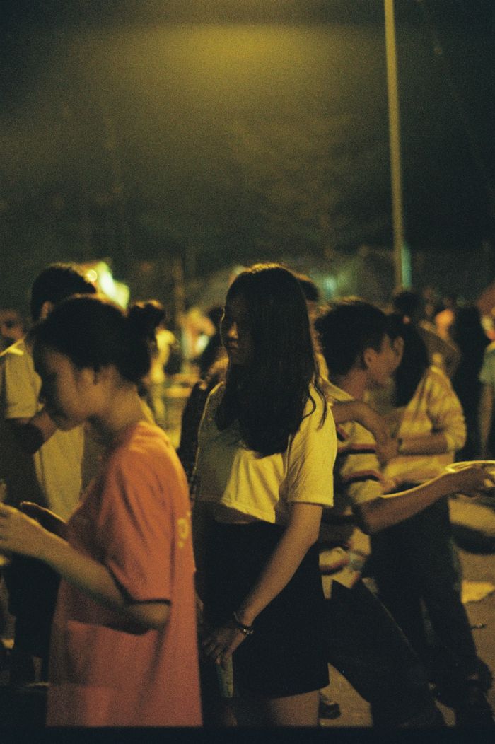 A vibrant street scene at night with diverse people enjoying a social gathering.